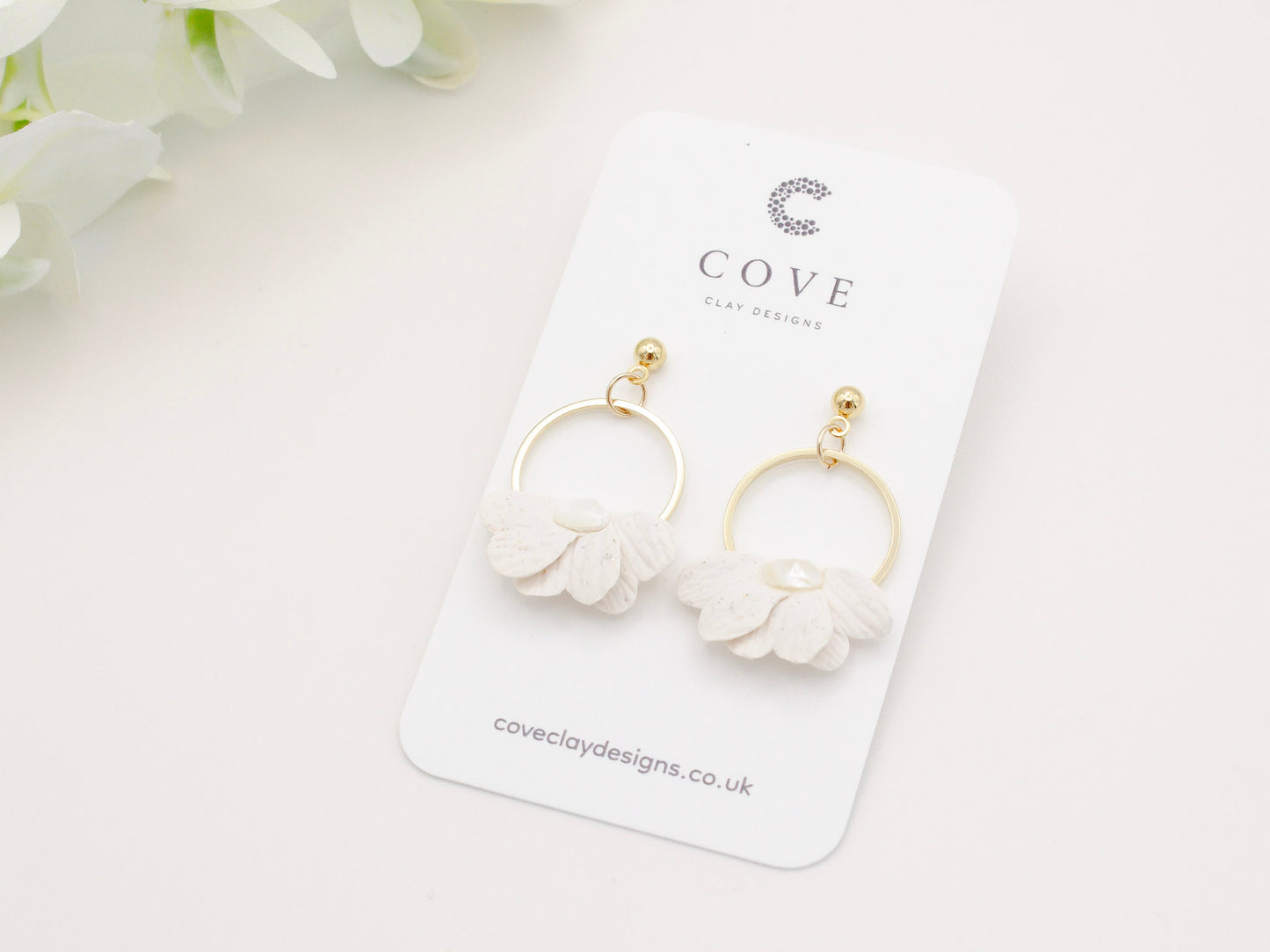 Handmade white petal hoop polymer clay earrings with gold stud posts.