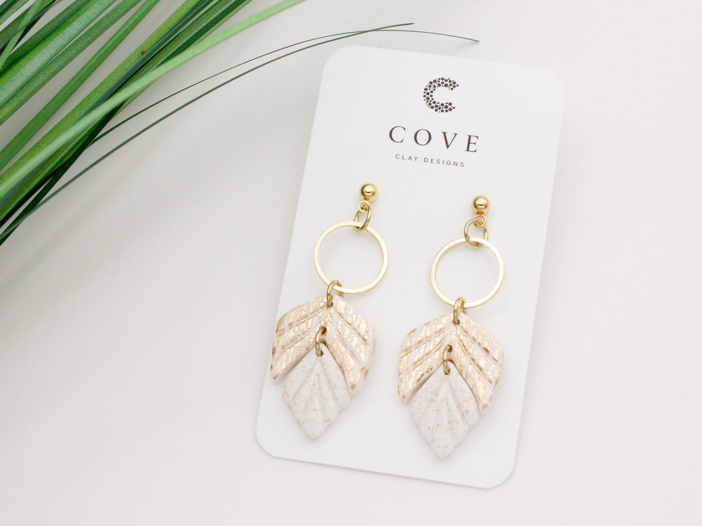 Handmade white and gold leaf clay earrings with gold hoop connectors.