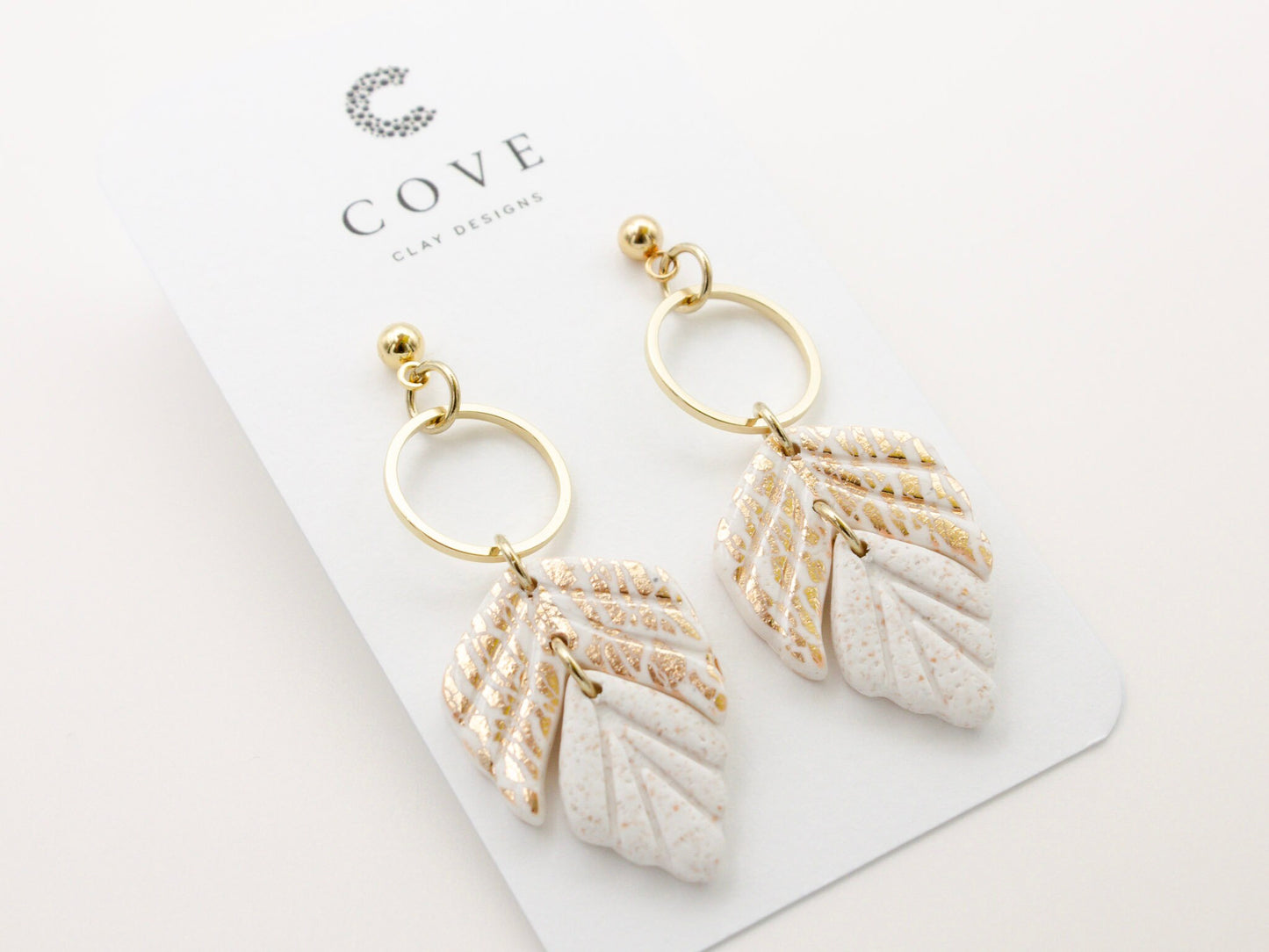 Handmade white and gold leaf clay earrings with gold hoop connectors by Cove Clay Designs