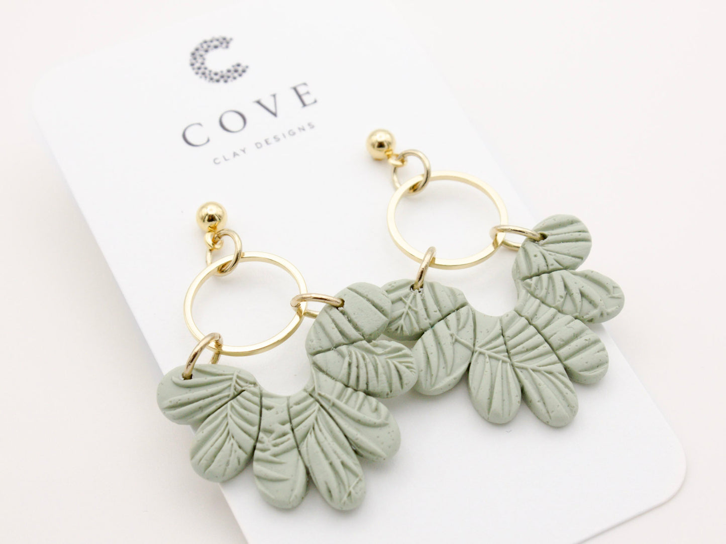 Handmade tropical green leaf polymer clay dangle earrings with gold hoop connectors by Cove Clay Designs