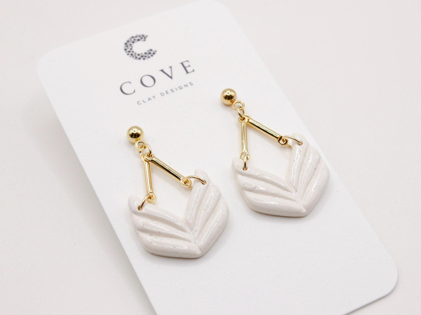 Handmade white geometric chevron dangle earrings with gold stud posts.