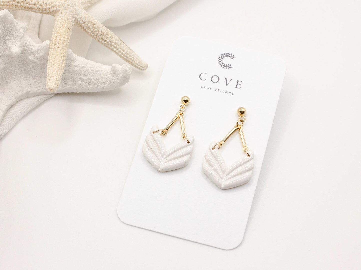 Handmade white geometric chevron dangle earrings with gold stud posts by Cove Clay Designs