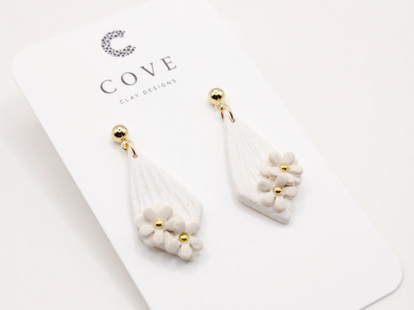 Handmade white diamond shaped polymer clay earrings with gold bar and mini flowers by Cove Clay Designs