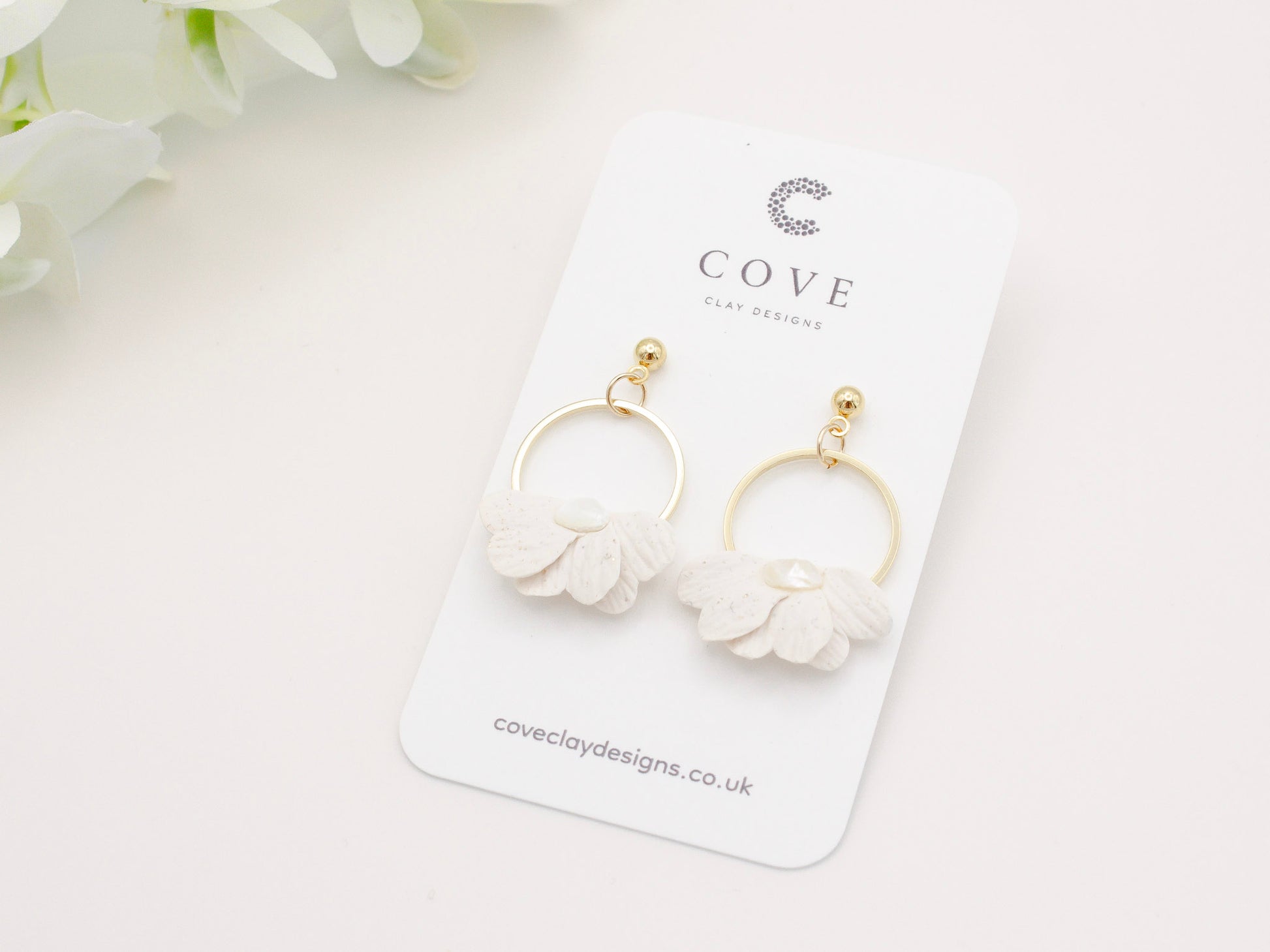 Handmade white petal hoop polymer clay earrings with gold stud posts.