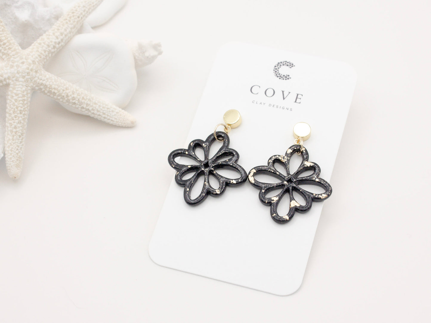 Handmade black and gold fleck debossed flower polymer clay earrings.