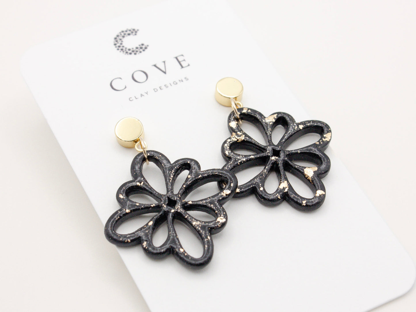 Handmade black and gold fleck debossed flower polymer clay earrings.