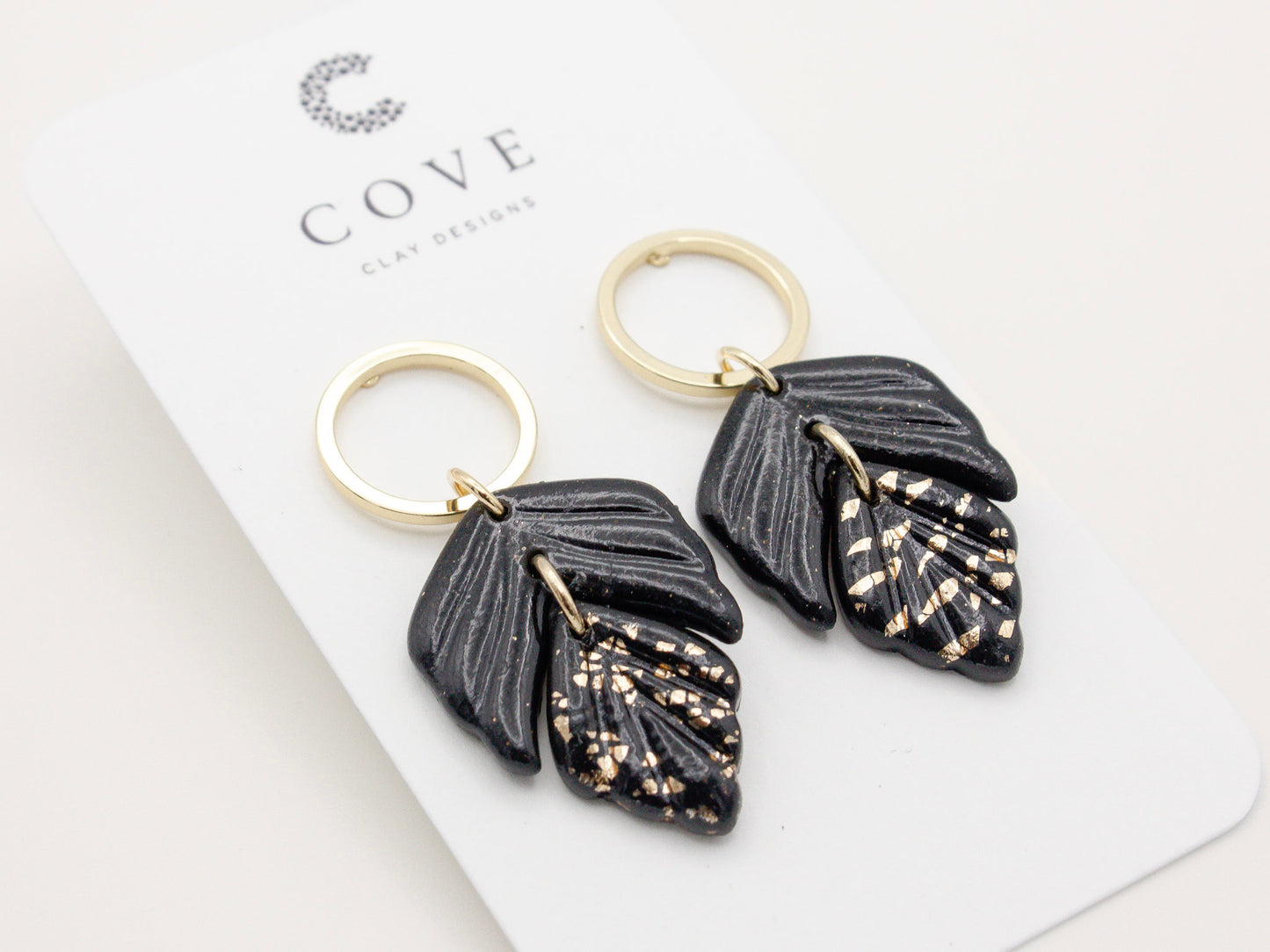 Handmade black and gold fleck double leaf polymer clay earrings.