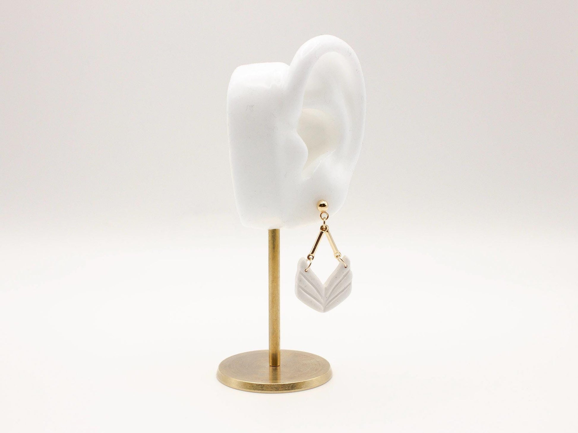 Handmade white geometric chevron dangle earrings with gold stud posts by Cove Clay Designs