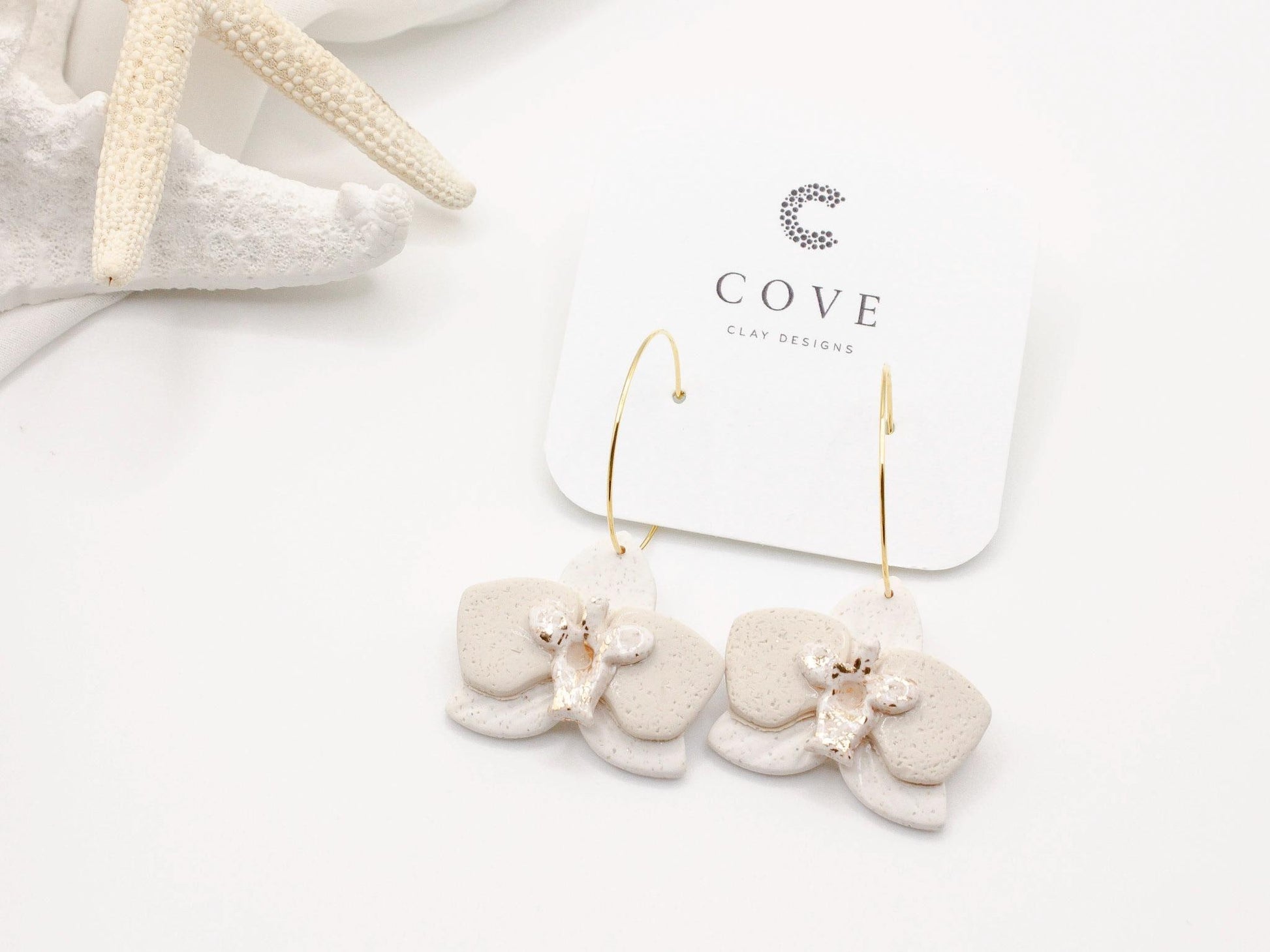 Handmade white orchid flower clay hoop earrings by Cove Clay Designs