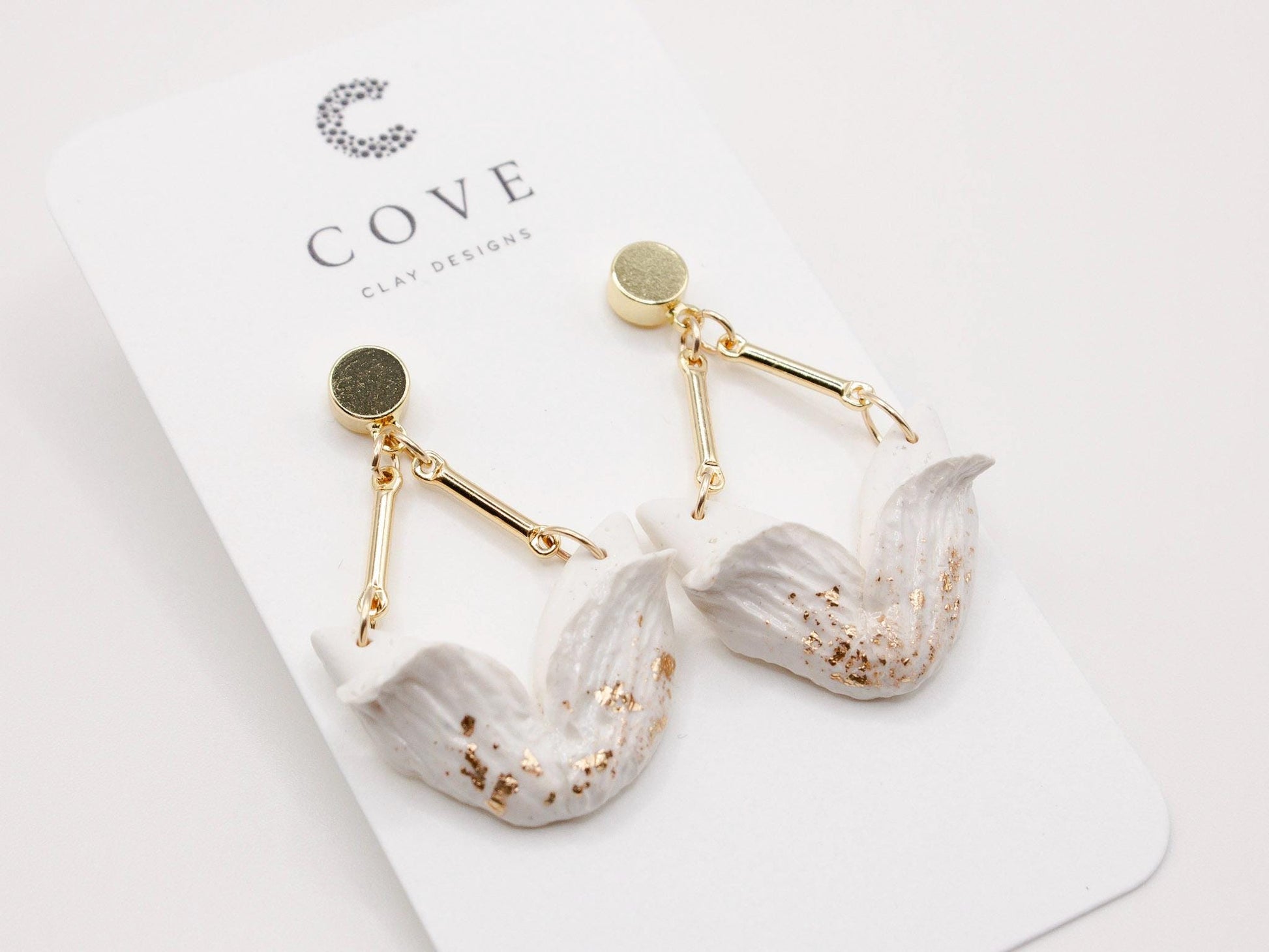 Handmade white tulip inspired clay dangle earrings with gold stud posts by Cove Clay Designs